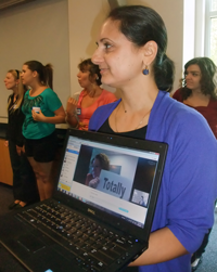 woman holding open laptop showing woman onscreen holding up sign that says the word Totally